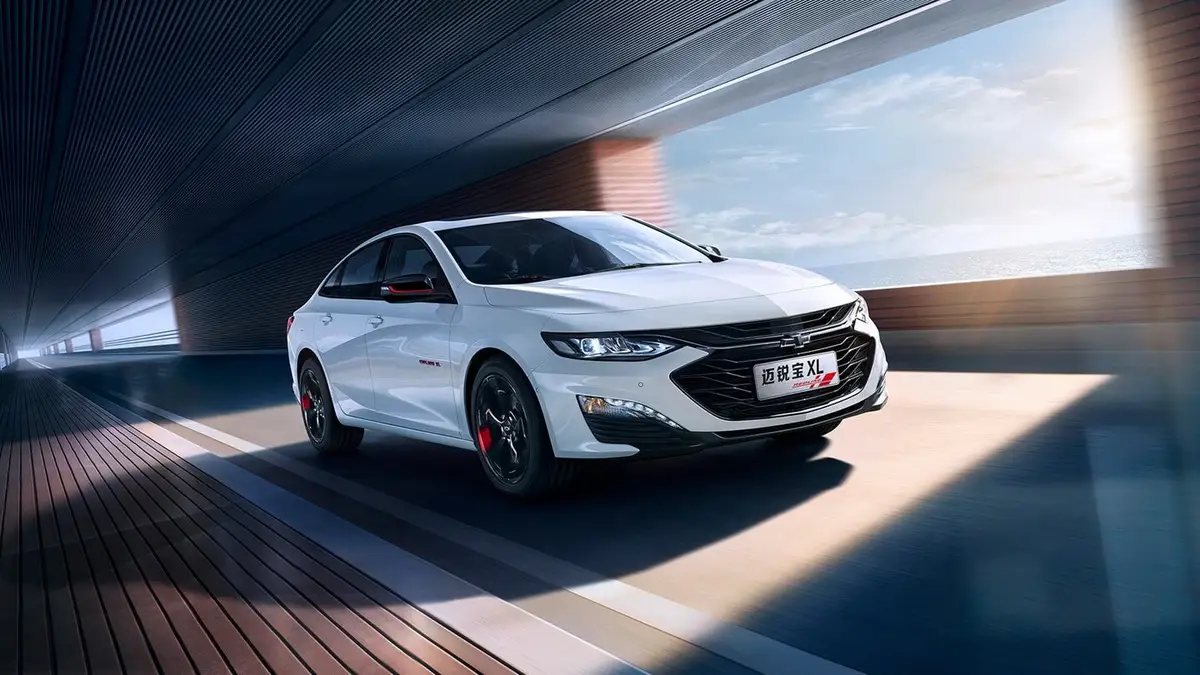 Chevrolet Malibu XL из Китая под заказ — белый седан под эстакадой, вид спереди в три четверти