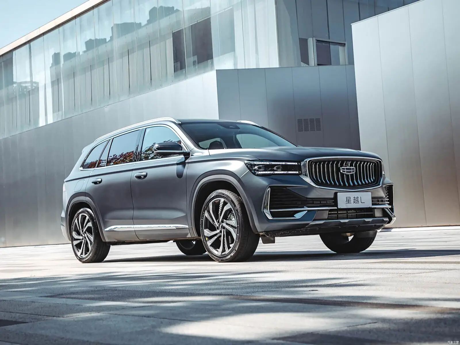 Тёмно-серый Geely Monjaro спереди сбоку у здания