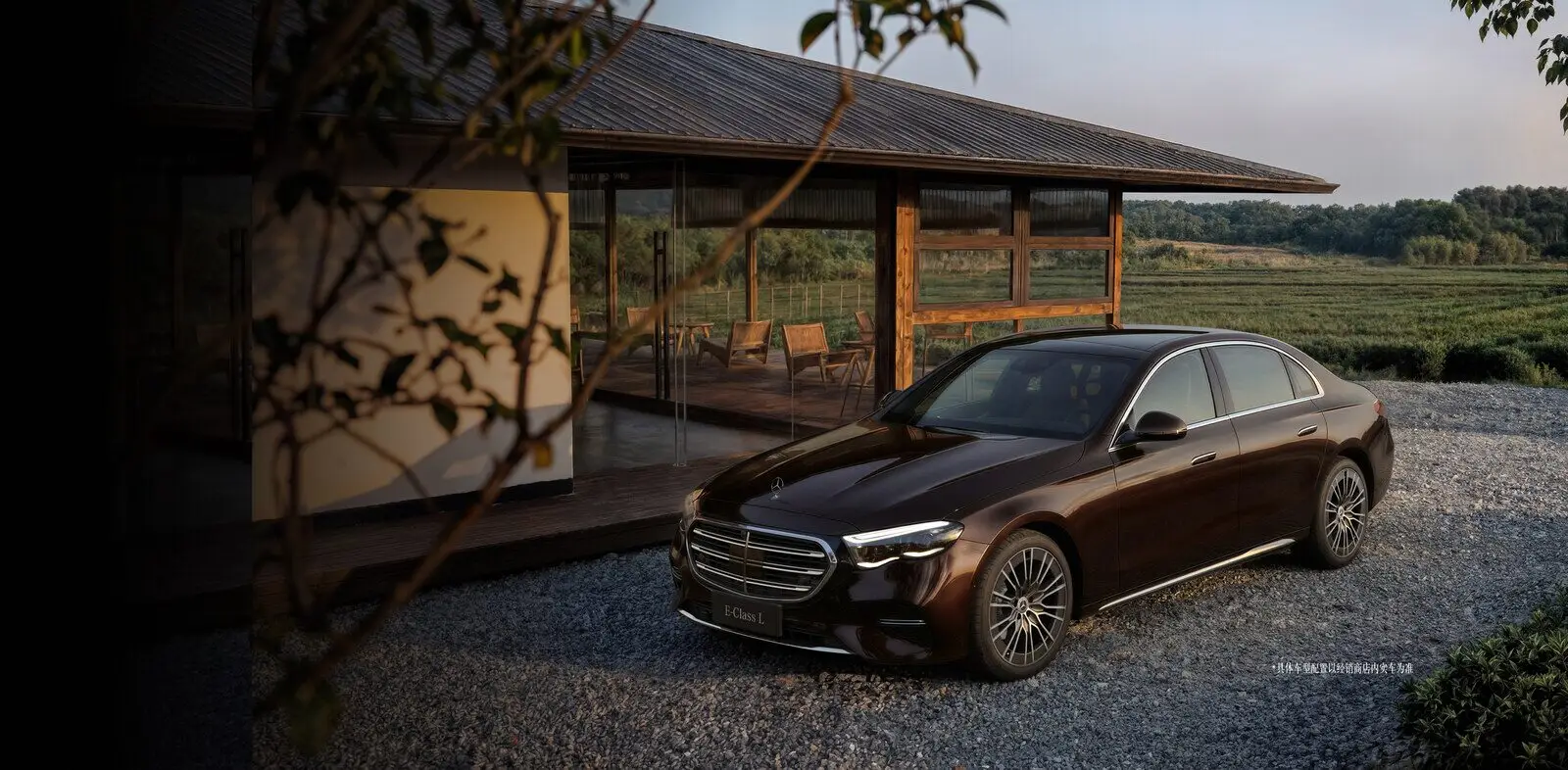 Тёмно-красный седан Mercedes-Benz E-Class L у дома с панорамными окнами
