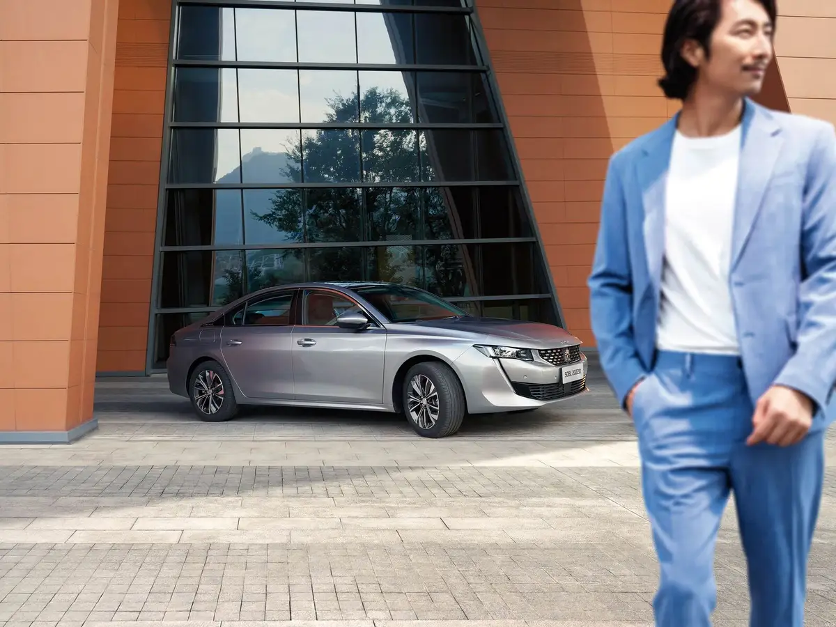 Peugeot 508 (Пежо 508) из Китая под заказ — Peugeot 508L, серый седан у здания, на переднем плане человек в голубом костюме