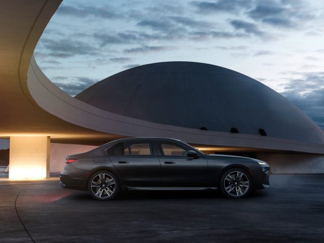 BMW 7 серии G70 в профиль у современной архитектуры
