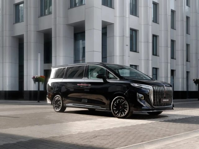 Чёрный HONGQI HQ9 у современного здания, вид спереди в три четверти